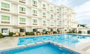 Um hotel com piscina, área de estar ao ar livre e um edifício de vários andares.