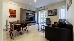 A modern living room with a dining area, a sofa, and a TV.