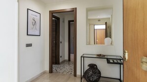 A hallway with a framed artwork, a mirror, a console table, and a door.