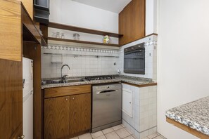 A compact kitchen with a dishwasher, stove, and oven. - San Giovanni House by Mmega (Florence)