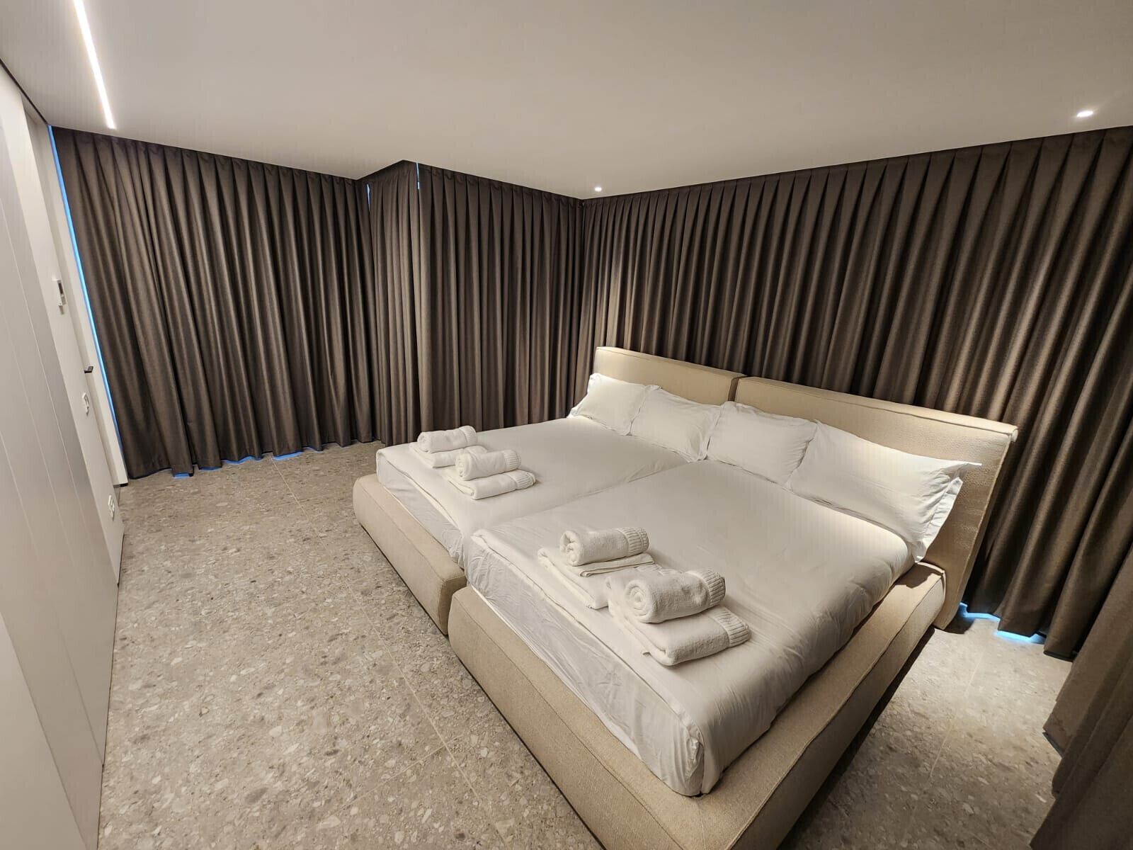 Une chambre spacieuse avec un grand lit, une banquette intégrée et une vue sur la ville par la fenêtre.