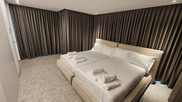 Une chambre spacieuse avec un grand lit, une banquette intégrée et une vue sur la ville par la fenêtre.