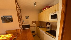 A compact kitchen with a wooden table, a microwave, a coffee maker, and a dishwasher.