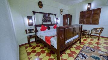 A bedroom with a bed, a wooden cabinet, a chair, and a patterned rug.