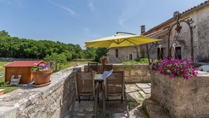 An outdoor patio with a table and chairs, a yellow umbrella, and potted plants.