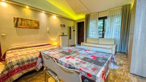 A bedroom with a bed, a sofa, a table, and a window with curtains. - Tabor - STUDIO  sleeps 4 (Bardonecchia)