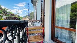 Un balcón con banca de madera, baranda metálica y vista a la montaña.