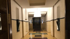 Ein Korridor mit einer Holztür links, einer Leuchte darüber und einem Schild mit der Zimmernummer 4.