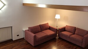 Ein Zimmer mit zwei roten Sofas, einer Stehlampe und einer Heizung.