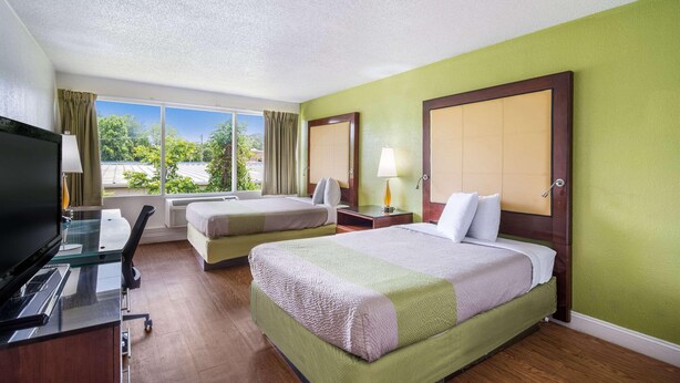 A hotel room with two beds, a desk, and a TV. - Econo Lodge Airport Near Billy Graham Parkway (Charlotte)