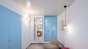 A bedroom with a bed, a blue wardrobe, a blue cabinet, and a small bathroom visible through a doorway.