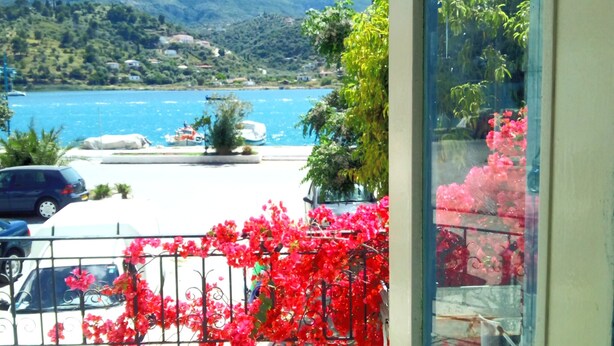 A balcony with a view of a lake, boats, and distant hills.