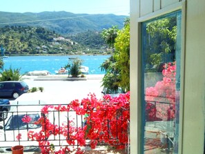 A balcony with a view of a lake, boats, and distant hills. - Ground floor of renovated townhouse with large veranda (Poros Town)