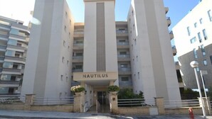 Un bâtiment moderne, avec une enseigne indiquant « NAUTILUS » à l’entrée. Il se distingue par un élément de design vertical central et de nombreux balcons.