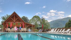 A pool area with lounge chairs and a wooden pavilion. - Cutest Wears Valley cottage that looks like it is straight out of a storybook! (Sevierville)