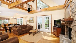 A spacious living room with a stone fireplace, wooden ceiling beams, and a cozy sofa. - Cutest Wears Valley cottage that looks like it is straight out of a storybook! (Sevierville)