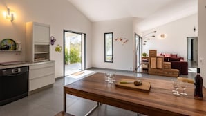 Une cuisine moderne avec une table à manger en bois, un four encastré et une grande fenêtre.