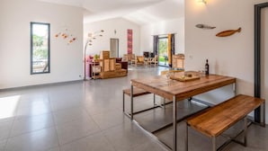 Un vaste espace de vie comprenant une table à manger en bois, des bancs et une vue sur l’extérieur.