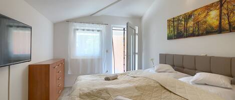 A bedroom with a bed, a dresser, a painting, and a window.