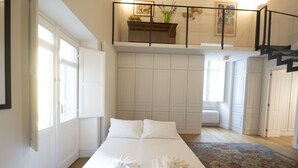 A spacious bedroom with a large bed, a view of the living area, and a staircase leading to an upper level. - Charm and Style by Campo de' Fiori (Roma)