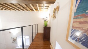 A wooden staircase with a glass railing, a green vase with branches, and a framed painting on the wall. - Charm and Style by Campo de' Fiori (Roma)