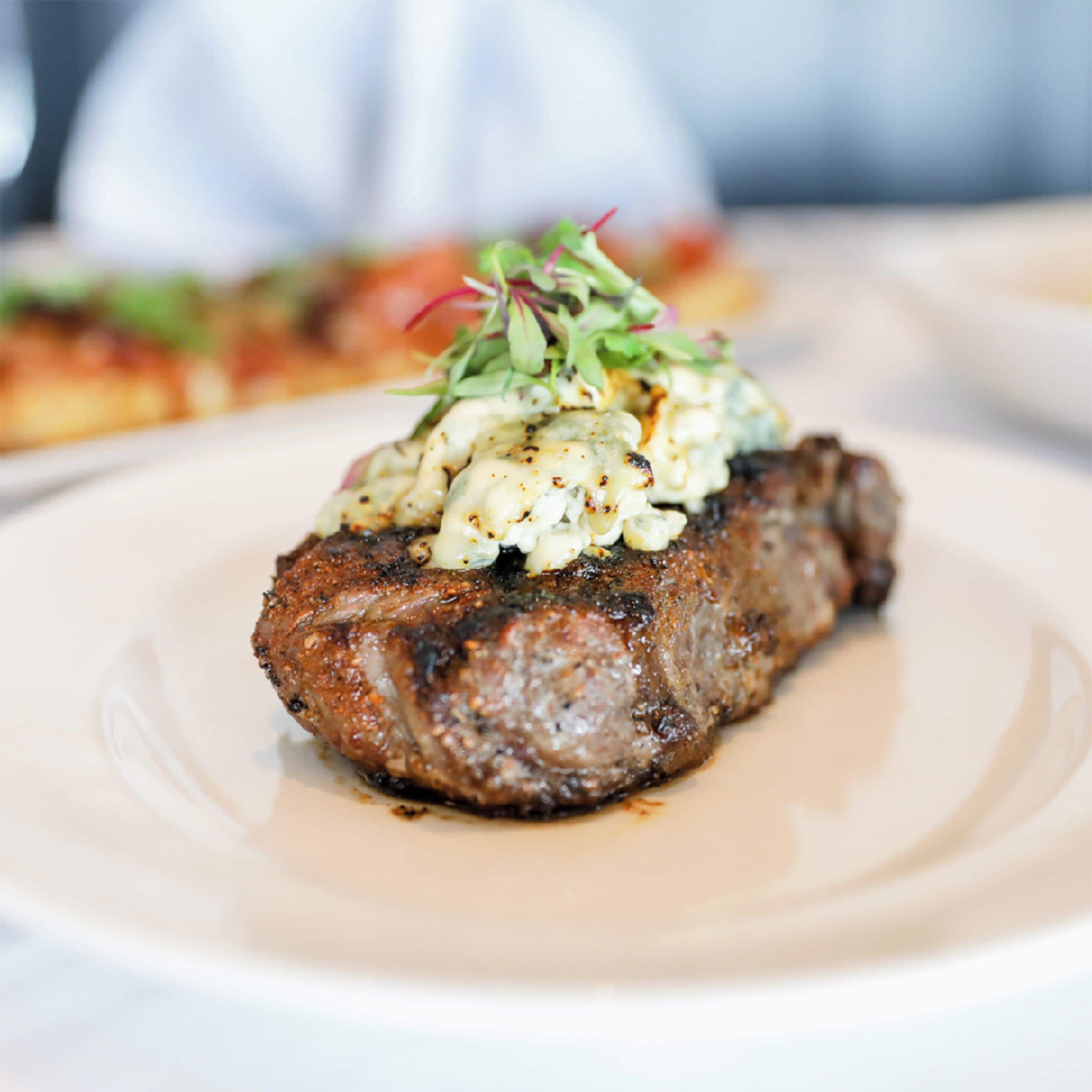 Een steak met romige saus en groenten op een bord.