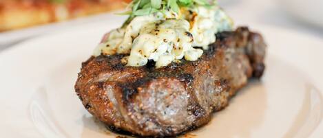 A steak with a creamy sauce and greens on a plate.