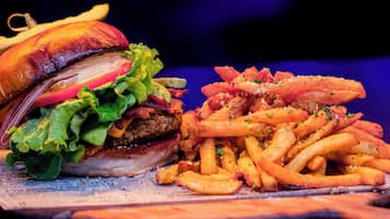Um hambúrguer com batatas fritas sobre uma tábua de madeira.