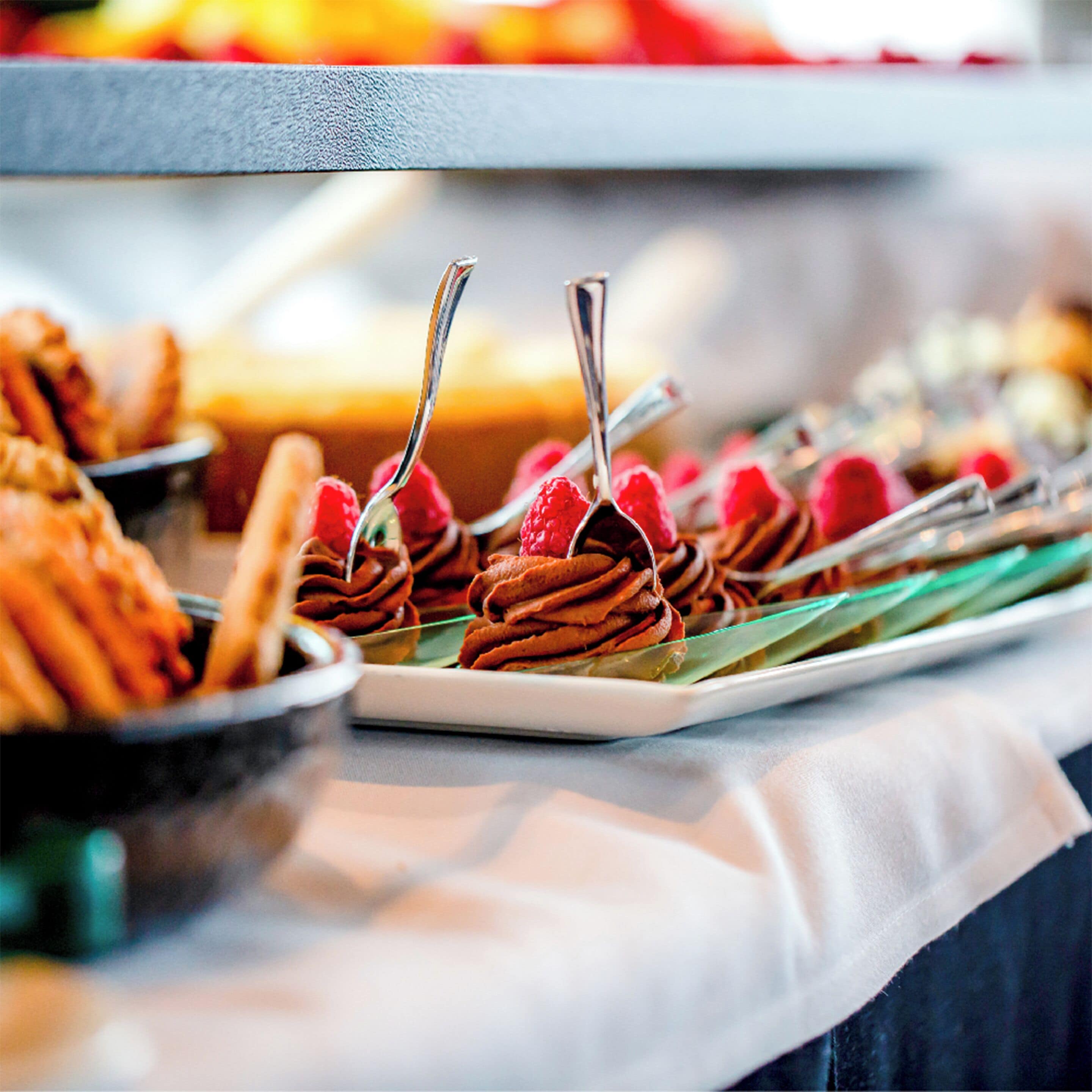 A buffet with various food items, including waffles and pastries, arranged on plates.