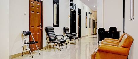 A hallway with black and brown chairs, a wooden door, and a ceiling fan.