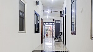 A clean, well-lit hallway with a tiled floor, a ceiling fan, and a chair near the end.