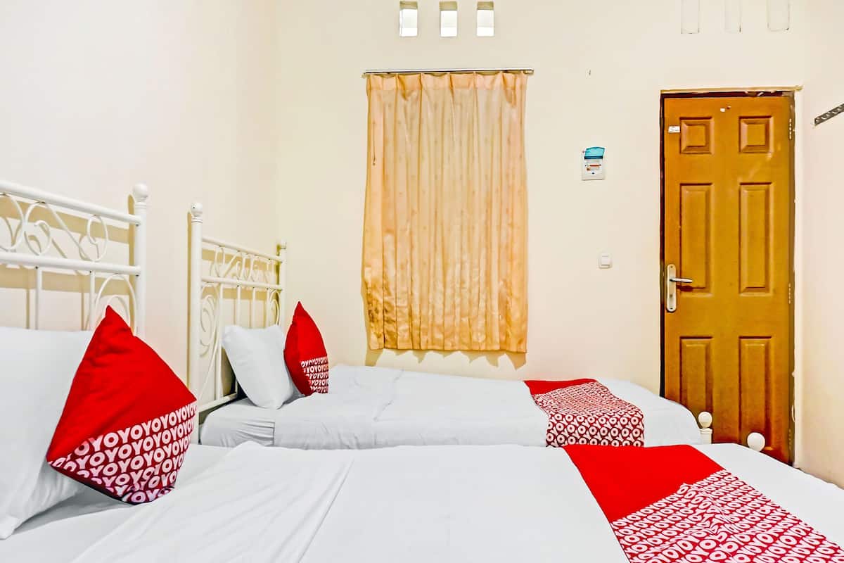 Un dormitorio con dos camas, una puerta de madera y una ventana con cortinas.