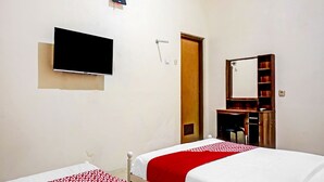 A hotel room with two beds, a TV, an air conditioner, a mirror, and a bookshelf.