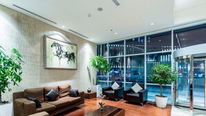 A modern lobby with a brown sofa, two armchairs, a coffee table, and potted plants. - Al Fattan - Sea View - Luxury JBR - Free Beach Resorts Access! (Dubai)