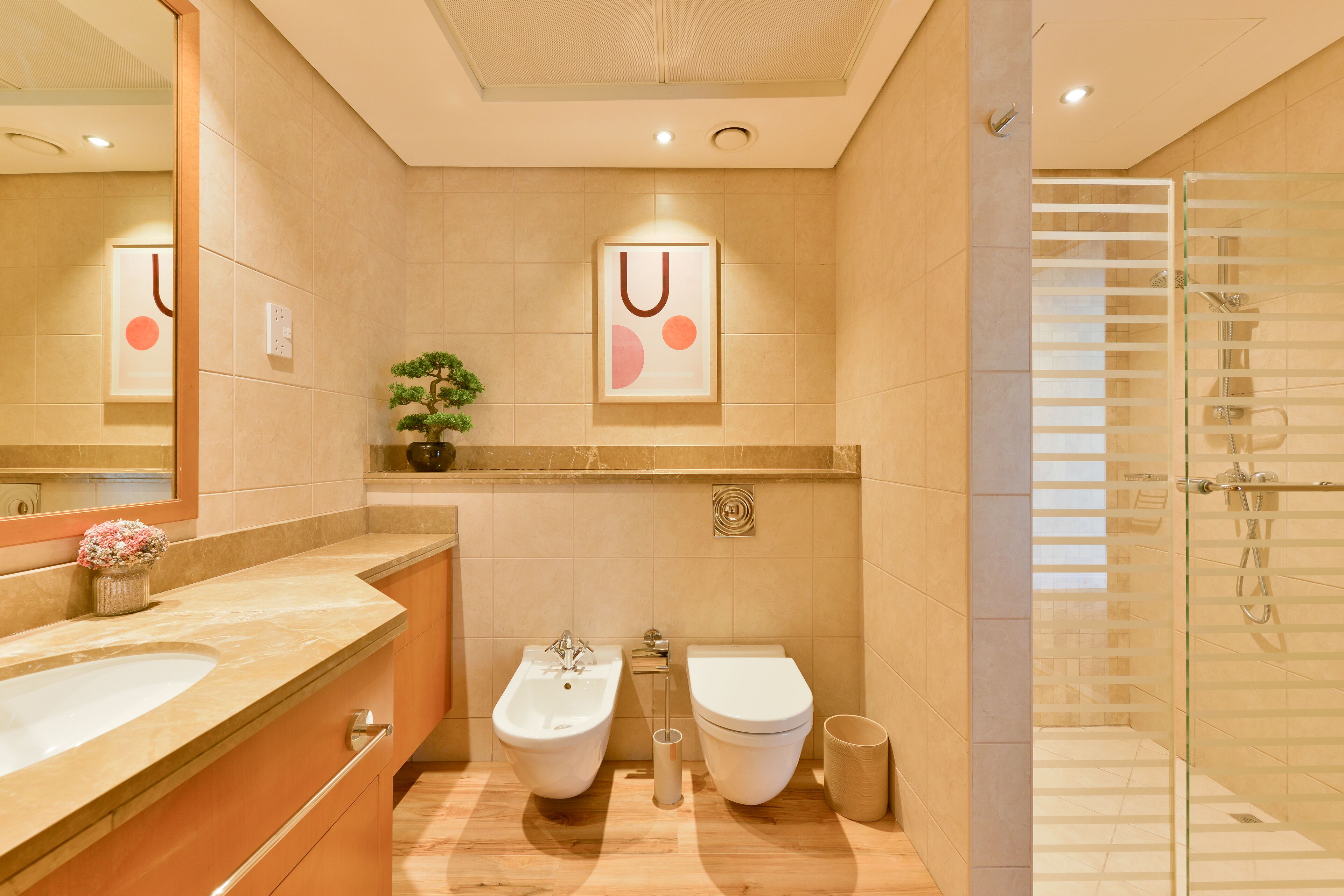 A modern bathroom with a bidet, toilet, and a glass shower enclosure.