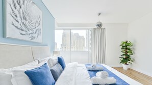 A modern hotel room with a large bed, a view of the city, and a potted plant. - Al Fattan - Sea View - Luxury JBR - Free Beach Resorts Access! (Dubai)