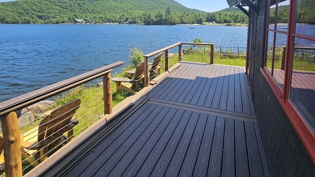 A wooden deck with a view of a lake and a forested hill. - Stunning Blue Mountain Lake - Waterfront Property! (Blue Mountain lake)