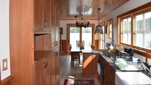A kitchen with wooden cabinets, a dining table, and a view of the outdoors. - Stunning Blue Mountain Lake - Waterfront Property! (Blue Mountain lake)