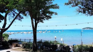 Blick auf die Küste mit blauem Himmel, Bäumen und einem Hafen mit Booten.