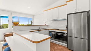 A modern kitchen with white cabinetry, a stainless steel refrigerator, and a large island with a wooden countertop. - SilverTide Retreat in Silverleaves (Silverleaves)