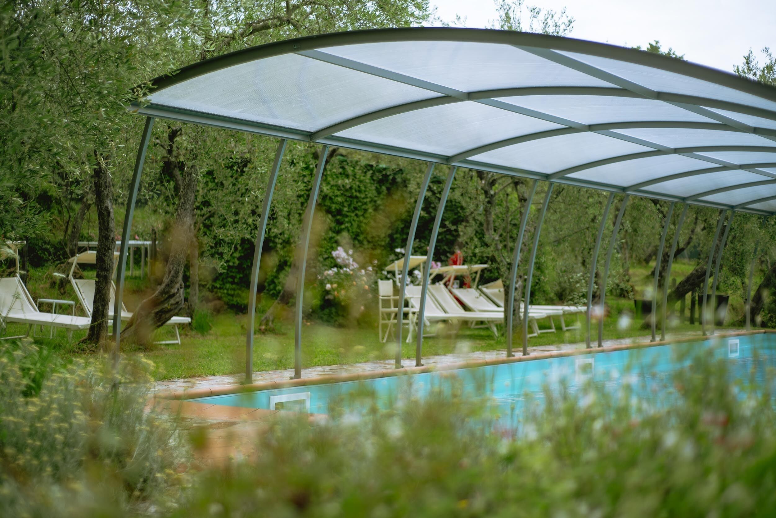 A covered swimming pool with lounge chairs and a canopy.