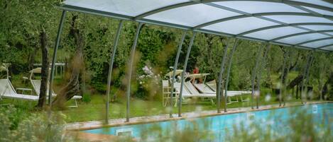 A covered swimming pool with lounge chairs and a canopy.