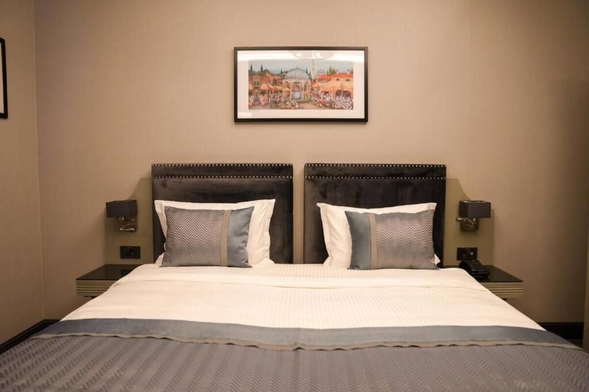 A double bed with a headboard, two bedside tables, and a framed picture on the wall.