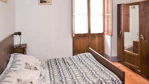 Una camera da letto con un letto, un armadio in legno, un comodino, una lampada e una finestra con tende.