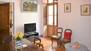 Una camera accogliente con un tavolo da pranzo in legno, sedie, televisore e opere d'arte alle pareti.