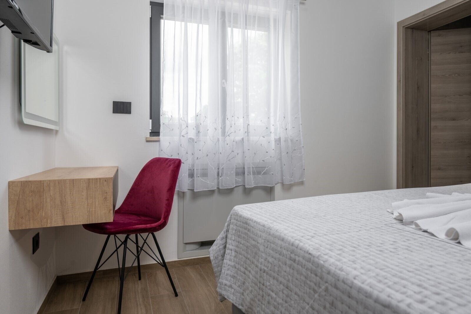 A bedroom with a bed, a desk, and a chair.