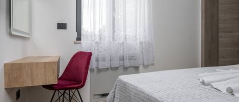 A bedroom with a bed, a desk, and a chair.