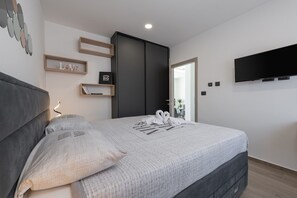 A modern bedroom with a large bed, a flat-screen TV, and a wardrobe.