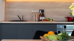 Cozinha moderna com bancada de madeira, máquina de café, garrafas de vinho e vegetais frescos.
