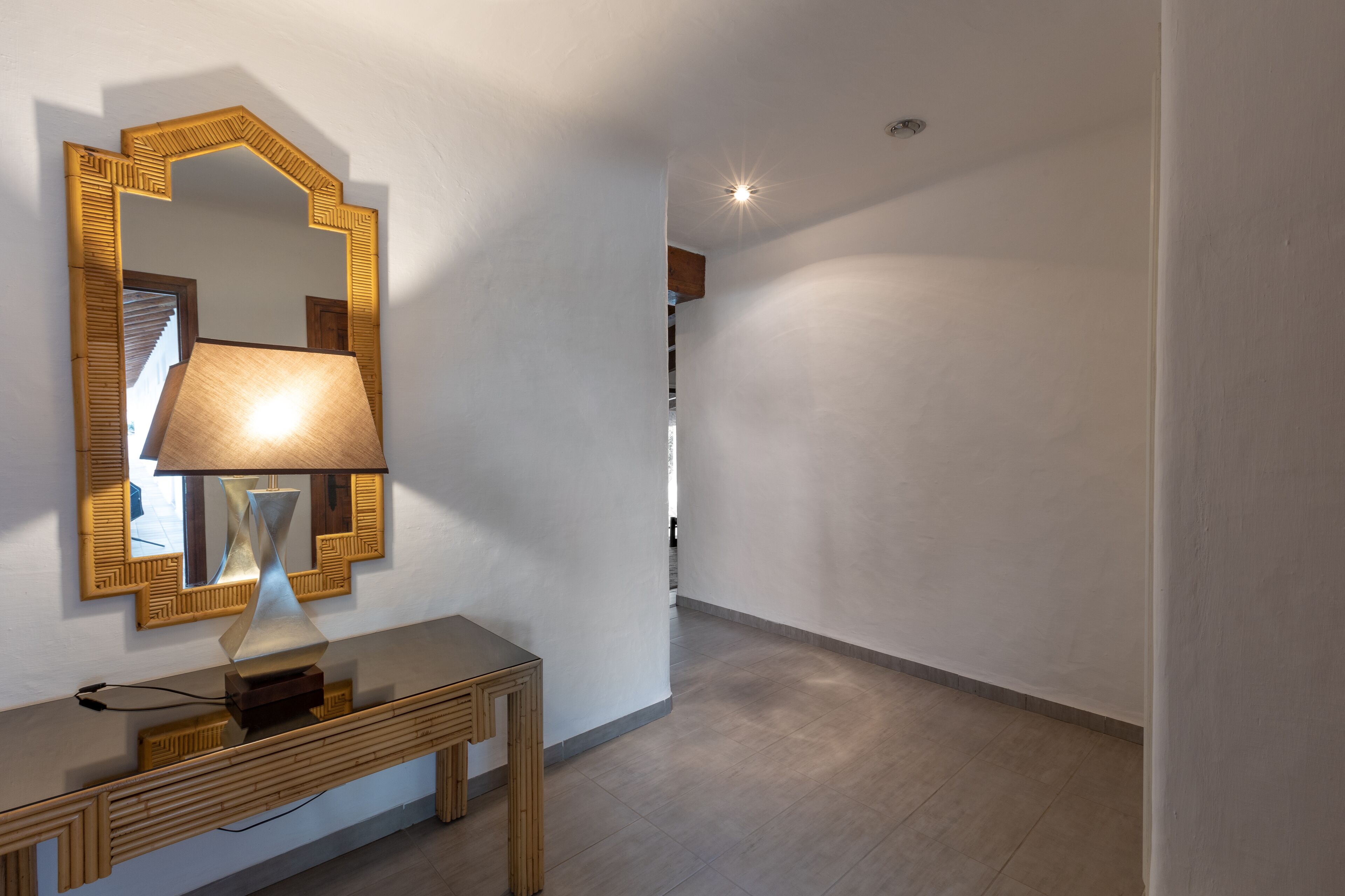 A hallway with a modern lamp, a mirror with a geometric frame, and a wooden console table.